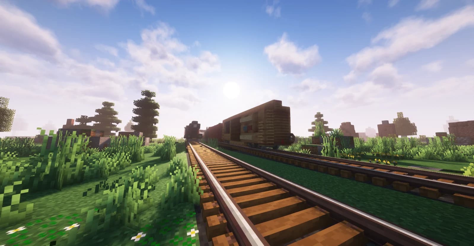 A Create railway through a green valley at sunset